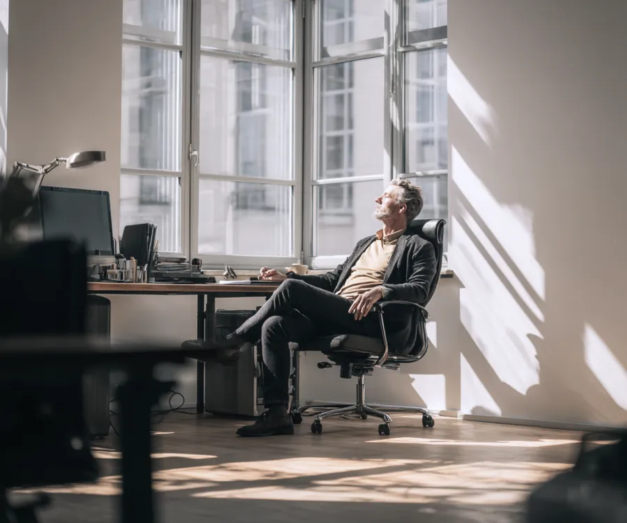A leader at ease by an office window